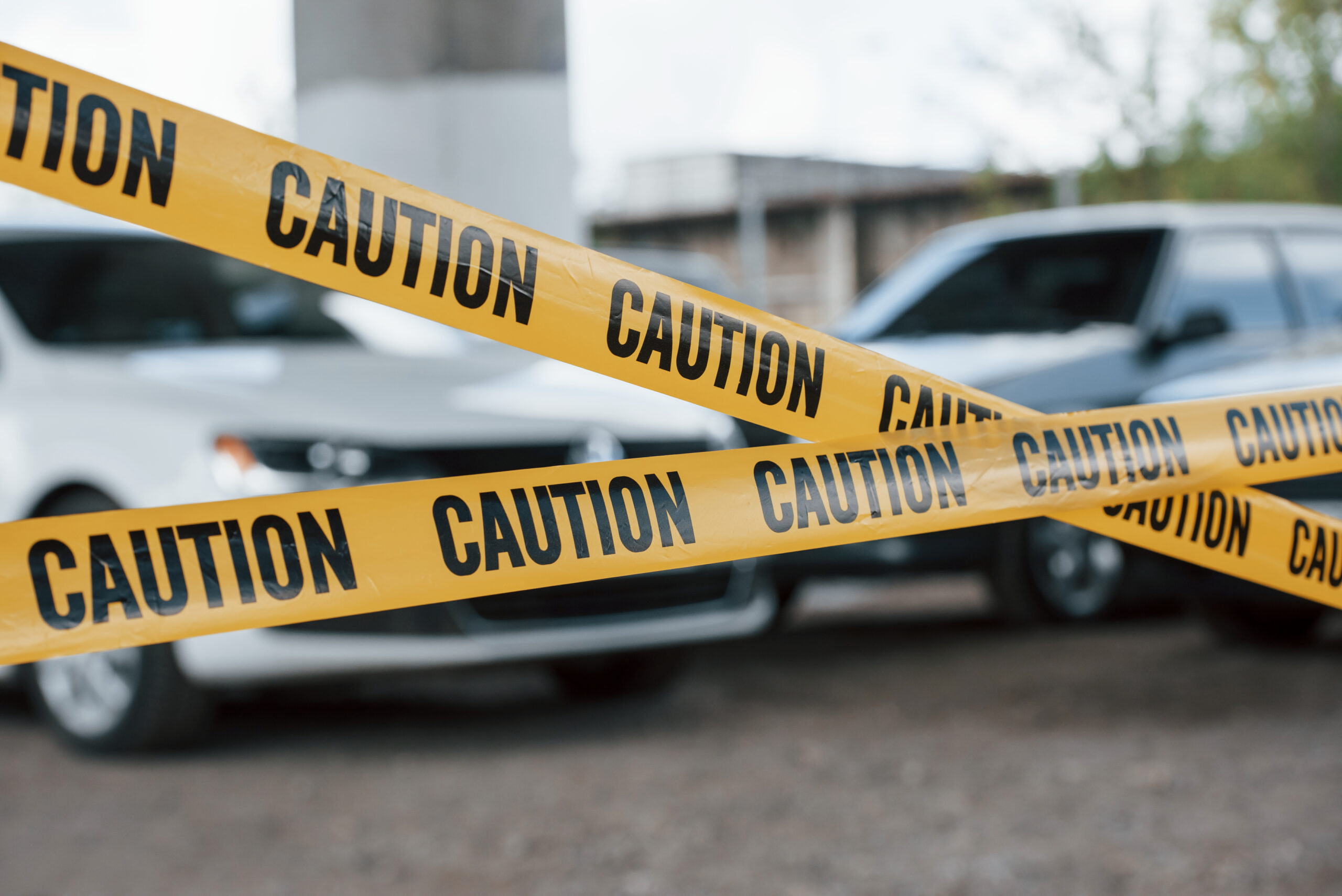 black white vehicles yellow caution tape near car parking lot daytime crime scene scaled